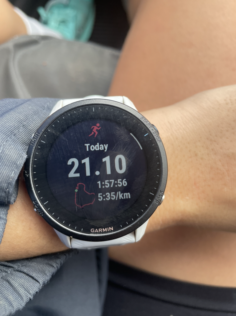 A runners Garmin watch reads data from their run, 21.1km in 1 hour and 57 minutes